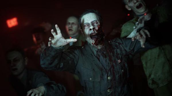 Screenshot from Resident Evil Veronica showing a group of zombies in a dark room, with one bloodied zombie reaching forward.