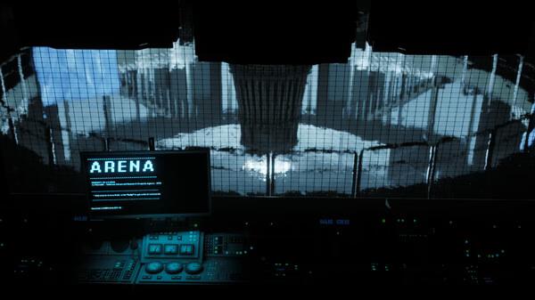 A screenshot from Beautiful Light showing a futuristic control room with glowing monitors and a view of a massive arena.