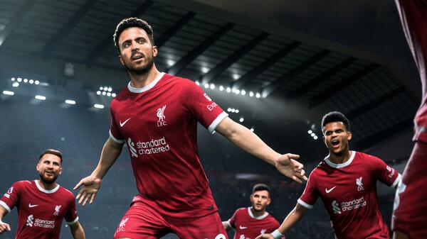 EA SPORTS FC 24 screenshot: A football player in a red jersey celebrates a goal with teammates in a brightly lit stadium.