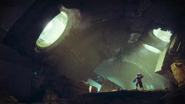 A Destiny 2 screenshot showing a Guardian standing in a mysterious, glowing cavern with large circular openings.