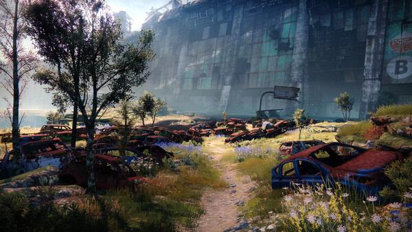 A Destiny 2 screenshot showing a lush field filled with rusted cars, trees, and a large ruined building in the background.