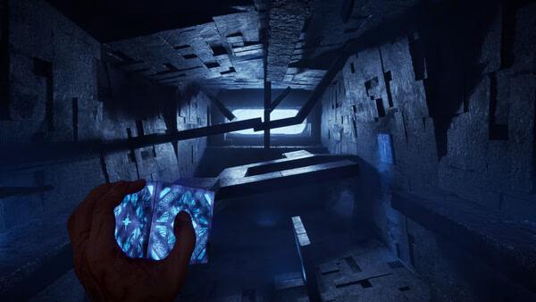 Clive Barker's Hellraiser: Revival screenshot of a hand holding a glowing puzzle box in a dark stone corridor.