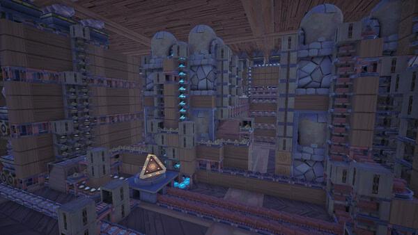 Alchemy Factory screenshot showing a towering voxel factory with glowing blue machines and a central triangular structure.