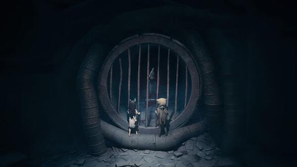 Screenshot from REANIMAL: Two characters stand in front of a large, circular barred gate in a dimly lit, mysterious setting.