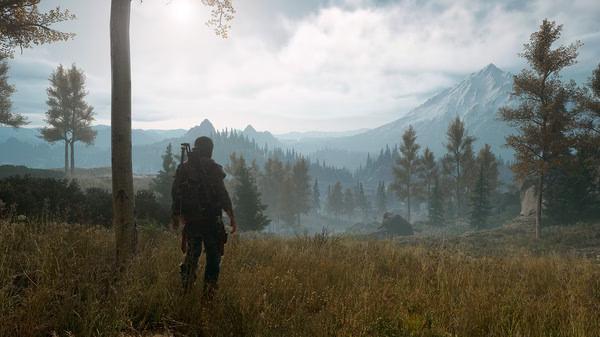 Days Gone screenshot: A lone biker stands in a lush, mountainous landscape with trees and distant peaks under a cloudy sky.