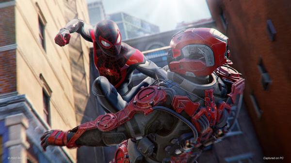 Screenshot from Marvel’s Spider-Man: Miles Morales showing Spider-Man mid-air, kicking an armored enemy on a city rooftop.