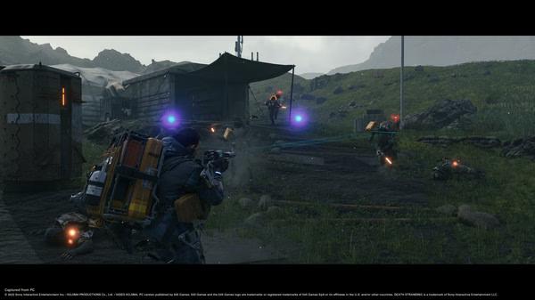 Screenshot from DEATH STRANDING DIRECTOR'S CUT showing Sam Bridges in combat, firing at enemies near a rugged campsite in a grassy landscape.