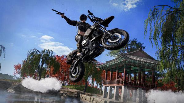 A PUBG: BATTLEGROUNDS screenshot showing a player on a motorcycle performing a jump near a pagoda with autumn trees in the background.