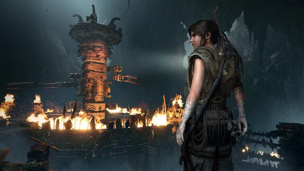 Shadow of the Tomb Raider screenshot: Adventurer stands before a flaming ancient mechanism inside a vast cavern.