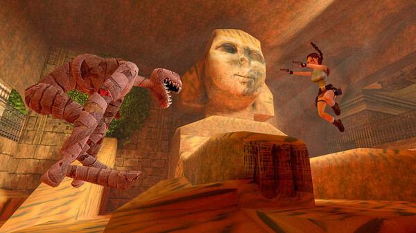 Screenshot from Tomb Raider I-III Remastered Starring Lara Croft. Lara Croft jumps towards a dinosaur in a cavernous environment.