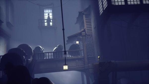 Screenshot from Little Nightmares showing a small figure in a yellow raincoat on a bridge, with a shadowy figure in a distant window.