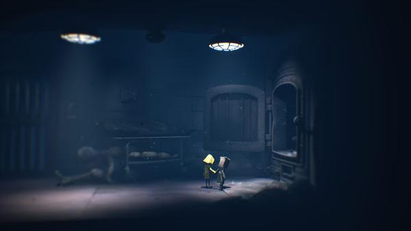 Screenshot from Little Nightmares II showing a dimly lit room with two small characters standing under a ceiling light.