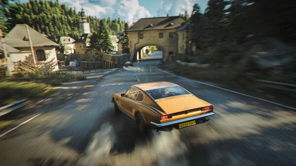 Screenshot from 007 First Light showing a yellow sports car drifting on a scenic countryside road near buildings and trees.