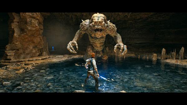 A screenshot from STAR WARS Jedi: Survivor™ showing a character with a lightsaber facing a large creature in a cave.