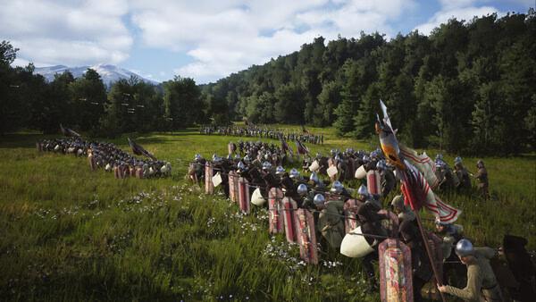 Screenshot from Manor Lords showing two medieval armies facing each other in a lush grassy field with trees and mountains in the background.