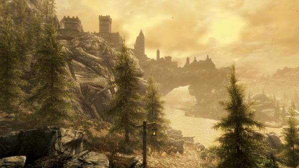 Screenshot from The Elder Scrolls V: Skyrim Special Edition showing a scenic landscape with a fortress and pine trees under a golden sky.