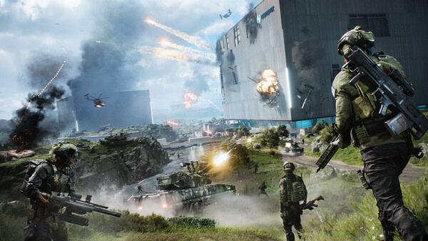 Screenshot from Battlefield™ 2042 shows soldiers advancing on a battlefield with helicopters and explosions around a large building.