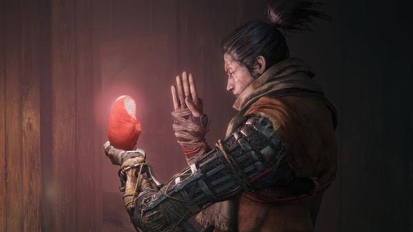 Screenshot from Sekiro™: Shadows Die Twice - GOTY Edition showing a character holding a glowing red object in their prosthetic hand.