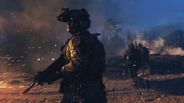 Call of Duty®: Modern Warfare® II screenshot showing soldiers in tactical gear amidst a smoky battlefield at dusk.