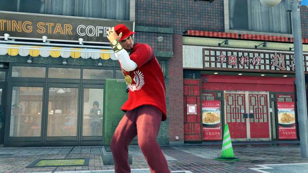 Screenshot from Yakuza: Like a Dragon showing a character in a red outfit and cap, posing on a city street.