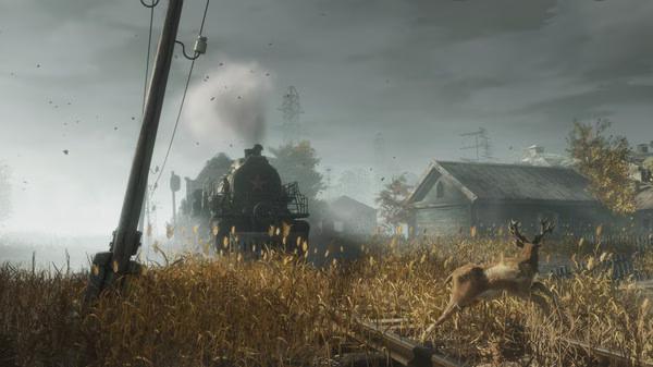 A screenshot from Metro Exodus showing a train in a rural area with tall grass, a deer in the foreground, and scattered buildings.