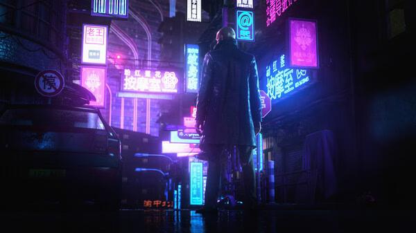 Agent 47 stands in a neon-lit street in a HITMAN World of Assassination screenshot, surrounded by vibrant signs.
