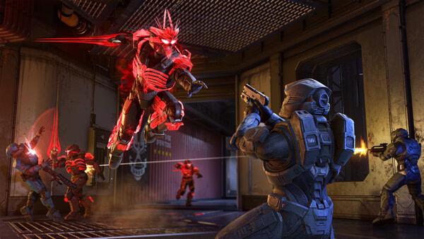 Halo Infinite screenshot showing a red Spartan lunging with an energy sword while blue Spartans fire weapons in a metallic interior setting.