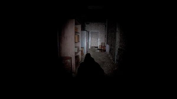 Unrecord screenshot: A dimly lit corridor with scattered boxes and barrels, leading to a closed door in the background.