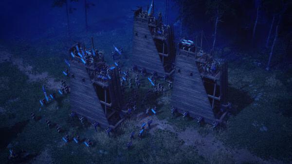 Anvil Empires screenshot: A night scene showing three wooden siege towers surrounded by soldiers in a forest clearing.