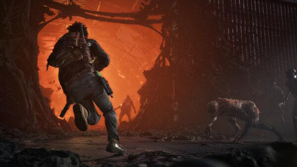 State of Decay 3 screenshot: A character runs towards a fiery entrance, pursued by zombie-like creatures in a dark, dilapidated setting.