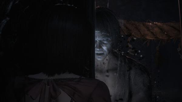 Screenshot from FATAL FRAME II: Crimson Butterfly REMAKE showing a ghostly figure facing a woman in a dark, eerie setting.