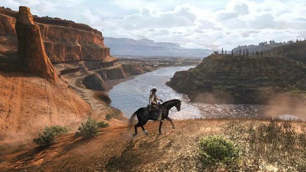 Red Dead Redemption screenshot showing a lone rider on horseback overlooking a scenic canyon and river landscape.