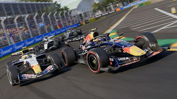 F1 25 screenshot: Close-up of Formula 1 cars racing on a sunny day, with detailed track and vibrant sponsor logos visible.