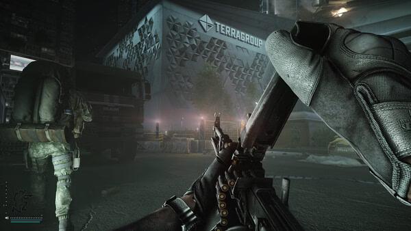 Escape from Tarkov screenshot: A player reloads their weapon while another character moves near a Terragroup building at night.