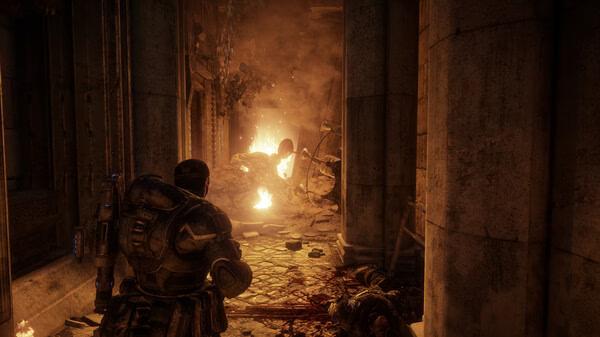 Gears of War: Reloaded screenshot showing a heavily armored soldier in a dimly lit corridor with rubble and fire in the background.