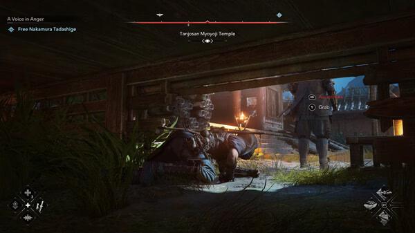 Assassin’s Creed Shadows screenshot: A player character crouches under a wooden structure, approaching guards near a lit temple at night.