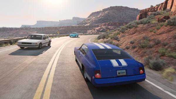 BeamNG.drive screenshot: A blue car with white stripes chases two vehicles on a winding desert highway surrounded by rocky terrain.