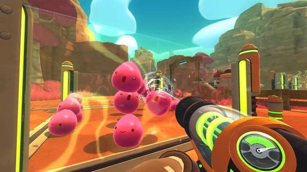Screenshot from Slime Rancher: A player uses a vacuum tool to capture smiling pink slimes in a vibrant, enclosed area.