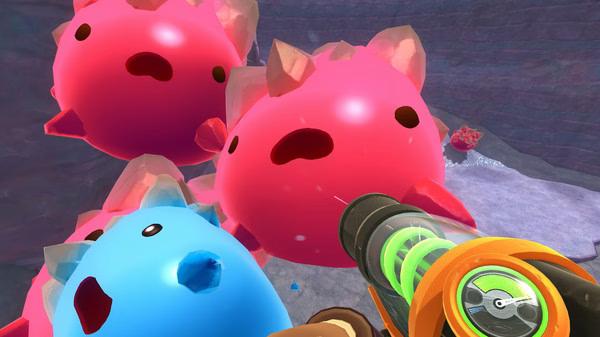 Screenshot from Slime Rancher showing several colorful, round slimes with crystal spikes in a rocky environment.