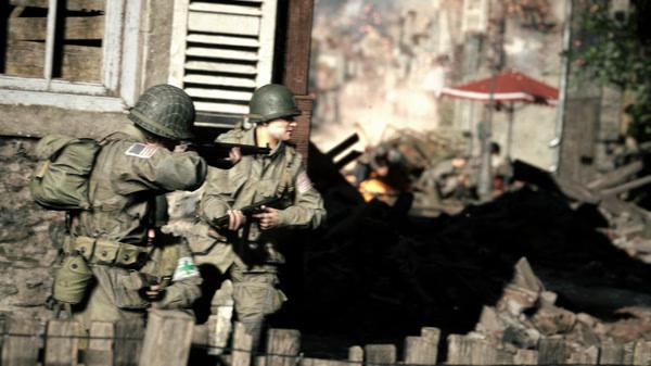 Soldiers in WWII gear advance through a war-torn street in a 'Hell Let Loose' screenshot, with rubble and buildings in the background.
