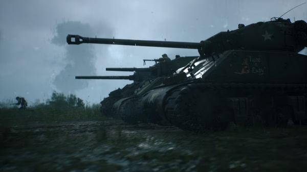 Hell Let Loose screenshot: Three tanks lined up in a rainy field, with soldiers visible in the background.