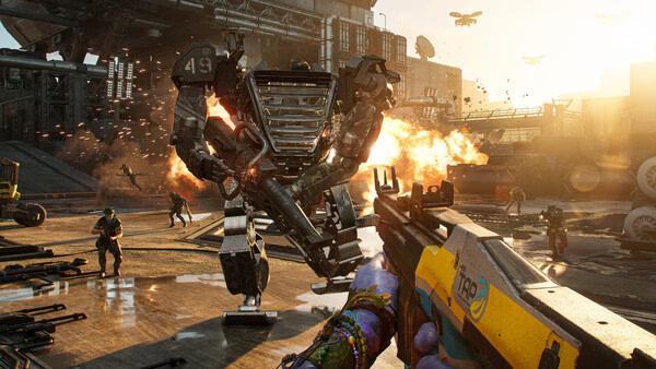 Screenshot from Avatar: Frontiers of Pandora showing a player aiming at a giant mech amidst explosions and chaos in an industrial setting.