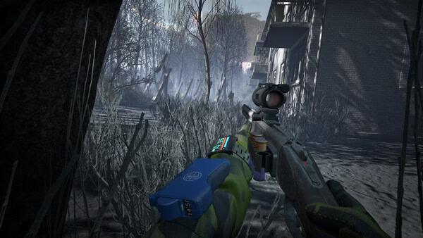 Into the Radius 2 screenshot: A player holds a scoped rifle, aiming through a foggy, desolate landscape with bare trees and a building.