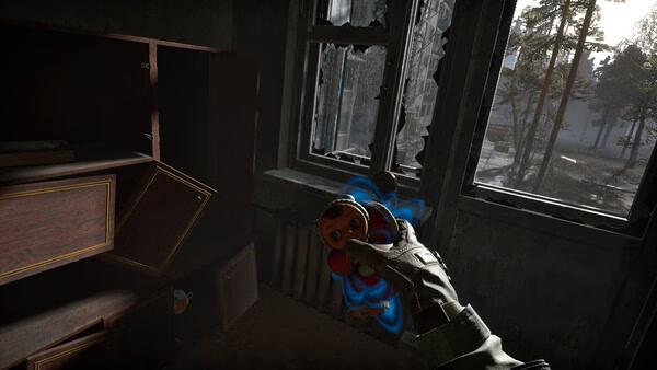 Screenshot from Into the Radius 2 shows a hand holding a doll in a dim room with broken windows and trees visible outside.