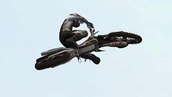 MX Bikes screenshot: A motorcyclist performs a high-flying stunt, showcasing dynamic action against a clear sky background.
