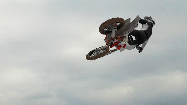 MX Bikes screenshot: A motorcyclist performs a high-flying stunt against a cloudy sky backdrop, showcasing dynamic gameplay.
