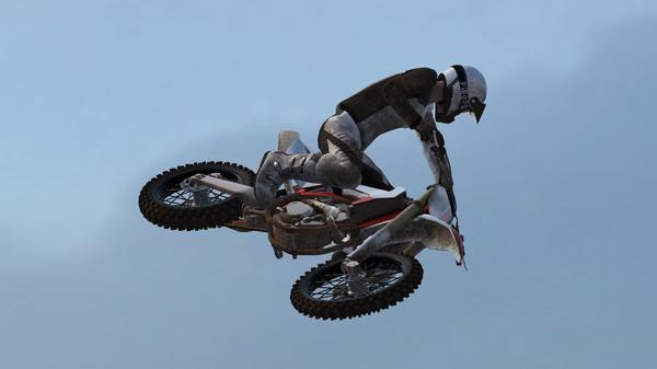 MX Bikes screenshot: A motocross rider wearing a helmet and gear performs a mid-air jump against a clear sky.