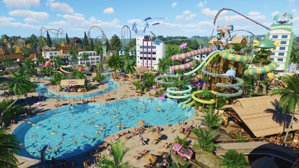 Screenshot from Planet Coaster 2 showing a lively water park with slides, pools, palm trees, and crowds enjoying a sunny day.
