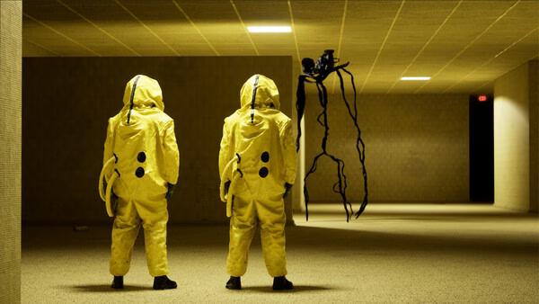Screenshot from Backrooms: Escape Together showing two players in yellow hazmat suits facing a shadowy, spider-like creature in a dim hallway.