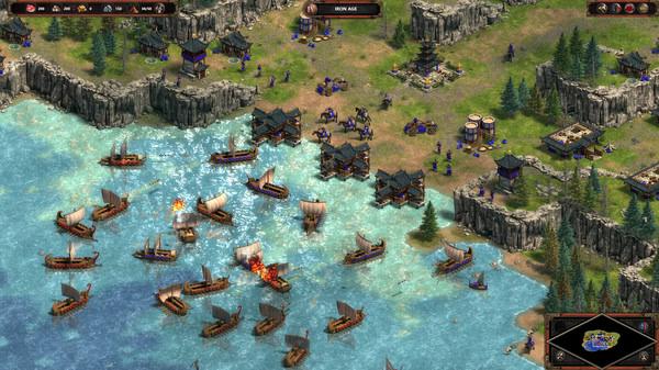 Screenshot from Age of Empires Definitive Edition shows a naval battle with multiple ships near a coastal settlement.